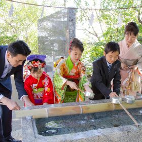 横浜の驚神社でお手水をする七五三記念日の家族